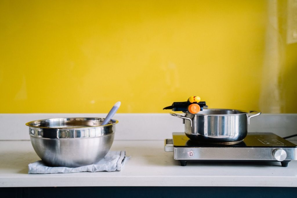 Cooking pots and utensils against a yellow kitchen wall