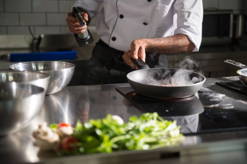 A person cooking with a frying pan on an induction hob